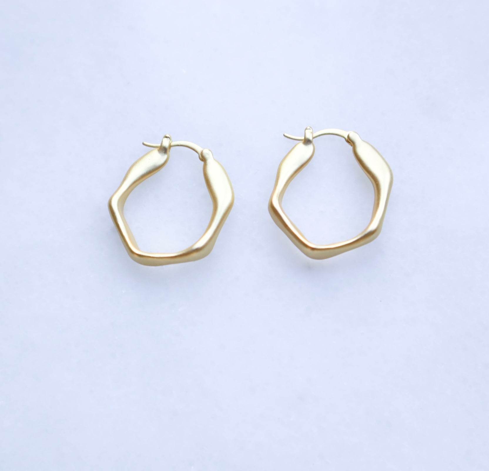 Gold hoop earrings on a light gray background